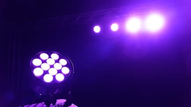 Rodie X12 LED wash light glowing violet on a theater stage with wash fixtures on the truss behind it
